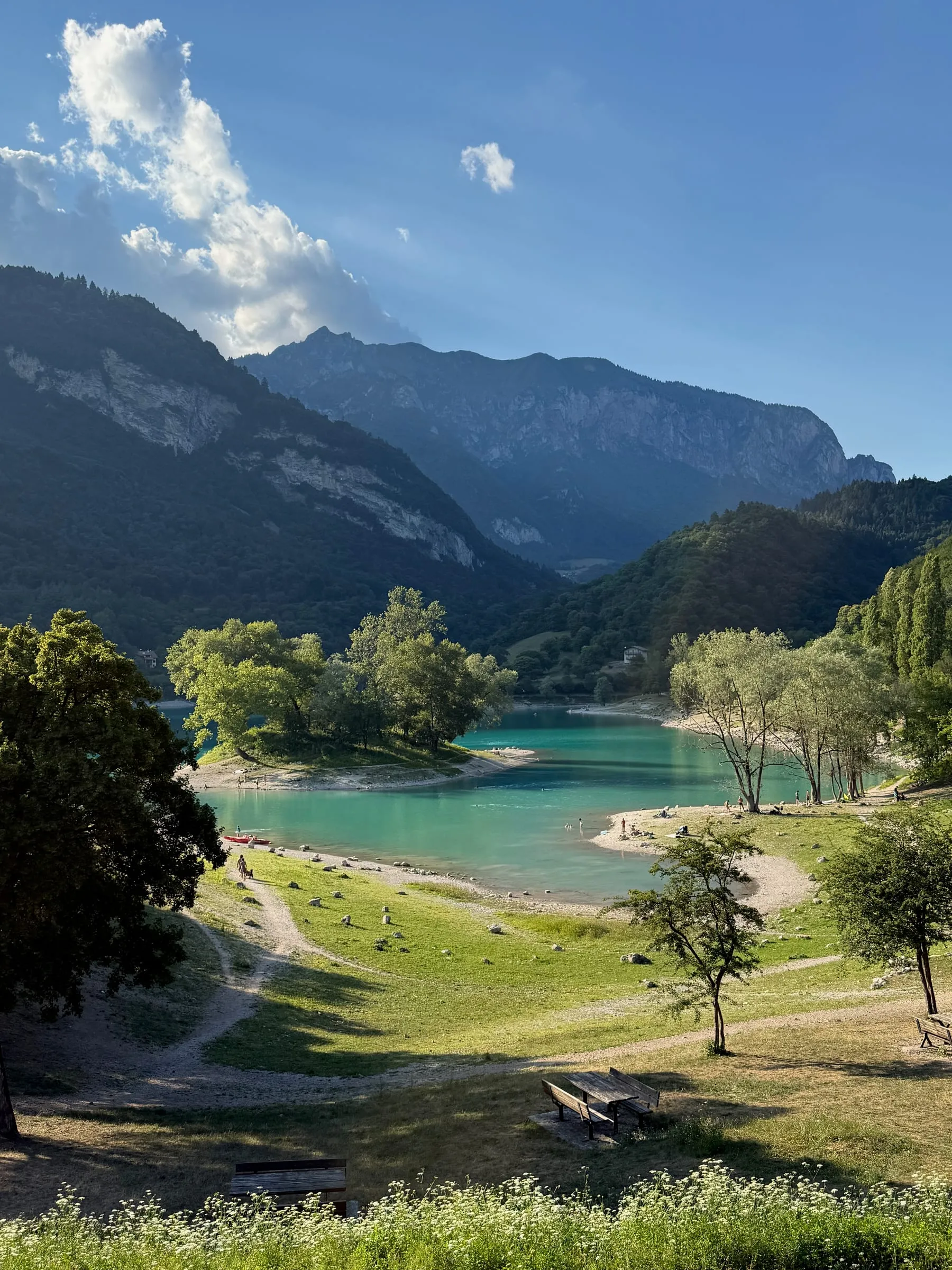 Turquoise water and a pale beach at Lago di Tenno, ringed by wooded mountains