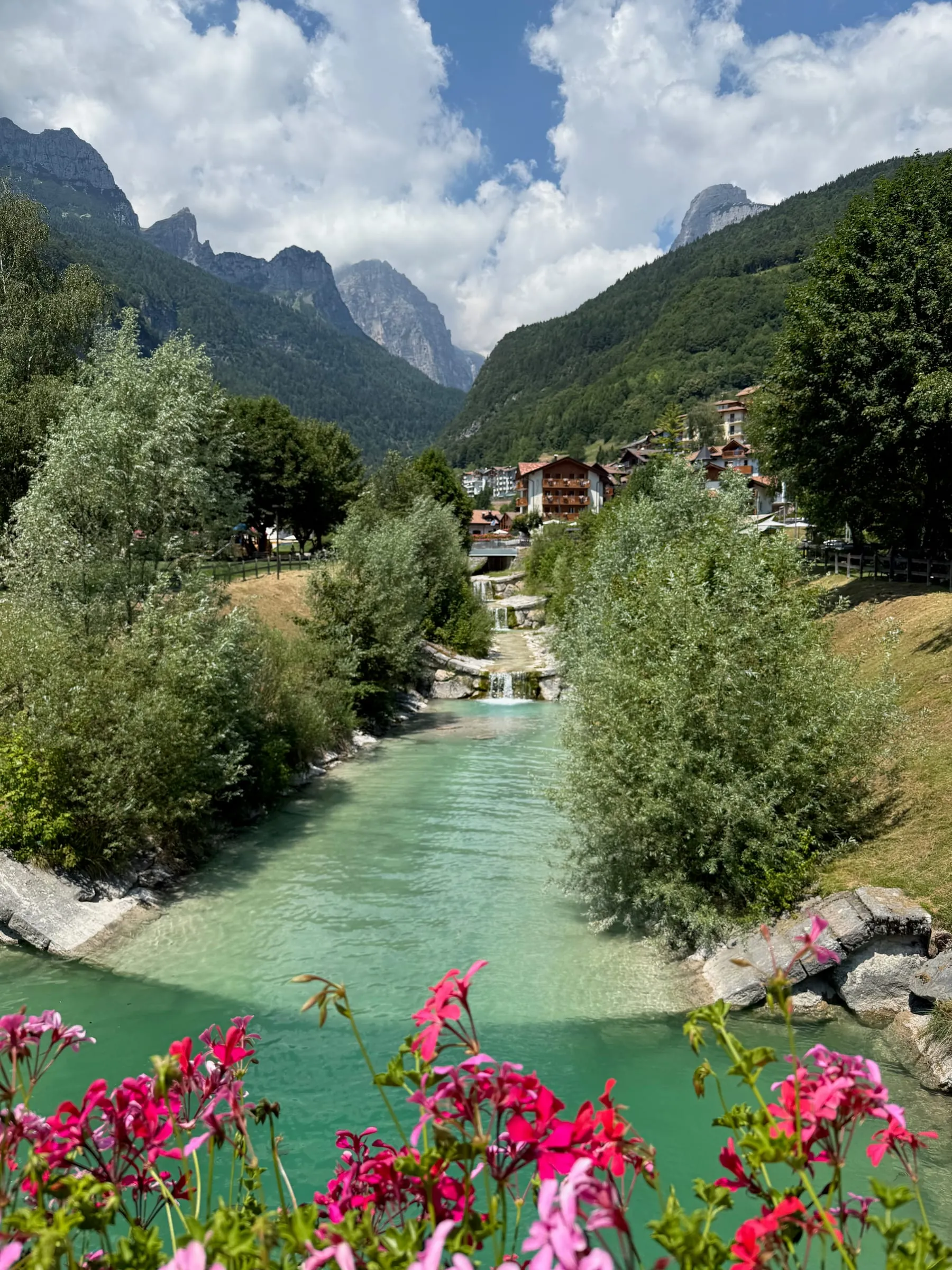 A green river running through Molveno with the Brenta peaks behind