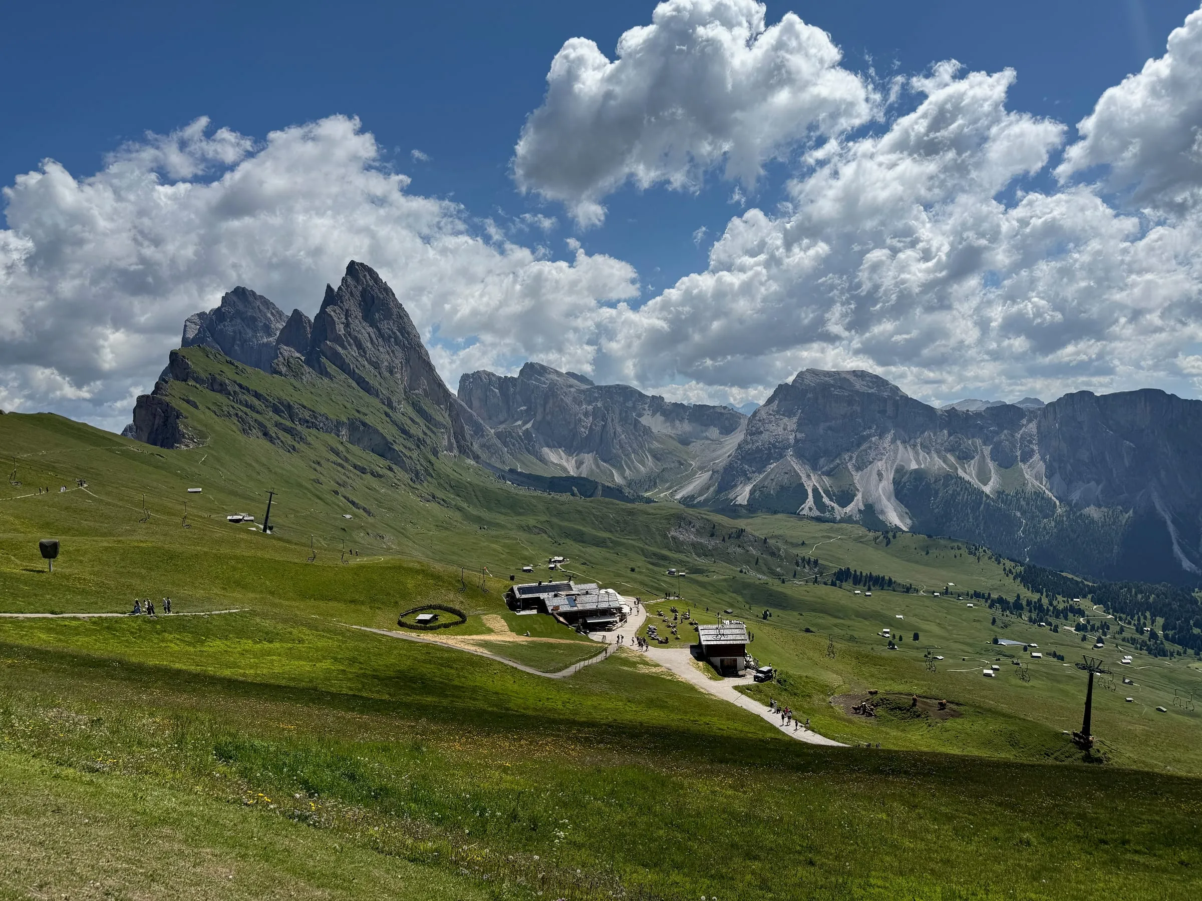 The Seceda ridge rising above green alpine meadows and a mountain hut